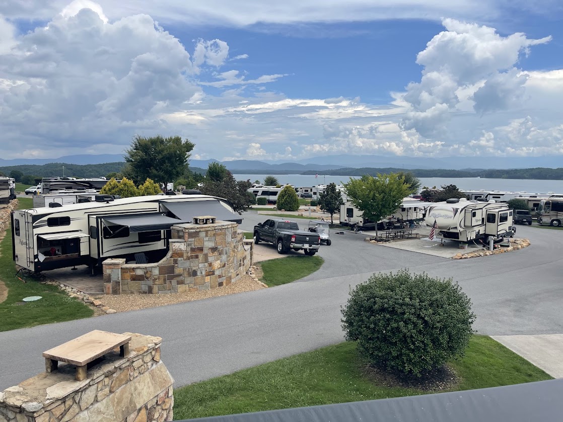 View of RVs around a stone circle, with scenic lake and mountains.