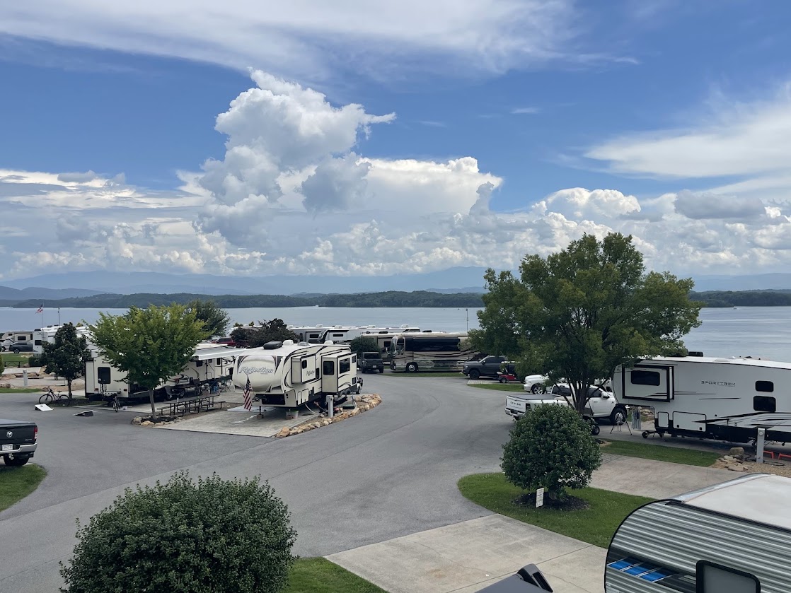 Close view of RVs with trees and lake visible in background.