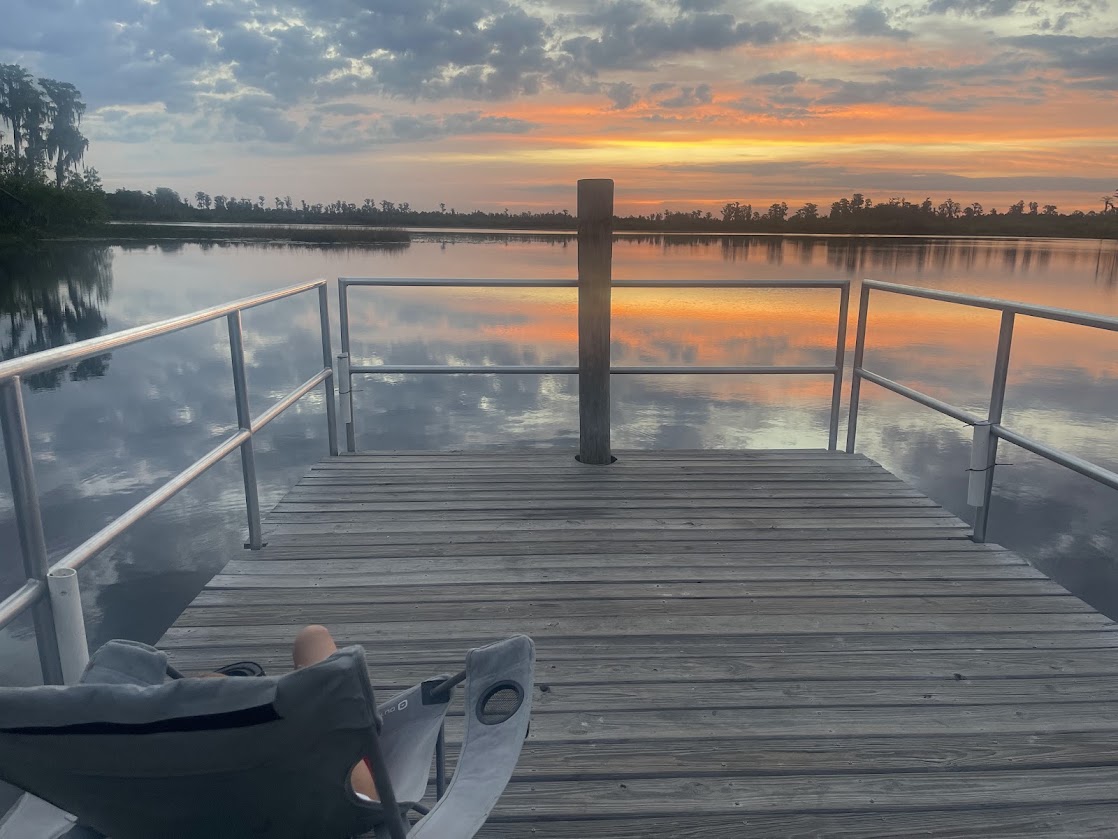 Sunset reflecting on calm water from a wooden dock.