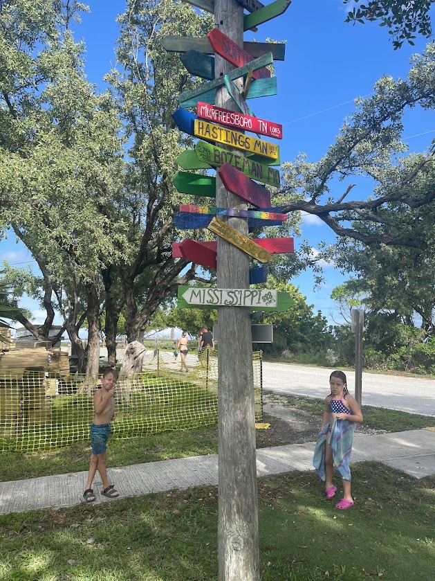 Directional signpost with colorful arrows, two children nearby.