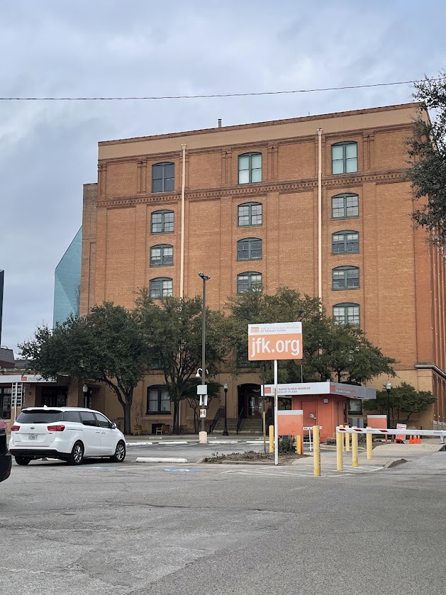 Exterior view of the Sixth Floor Museum building with a sign in front.