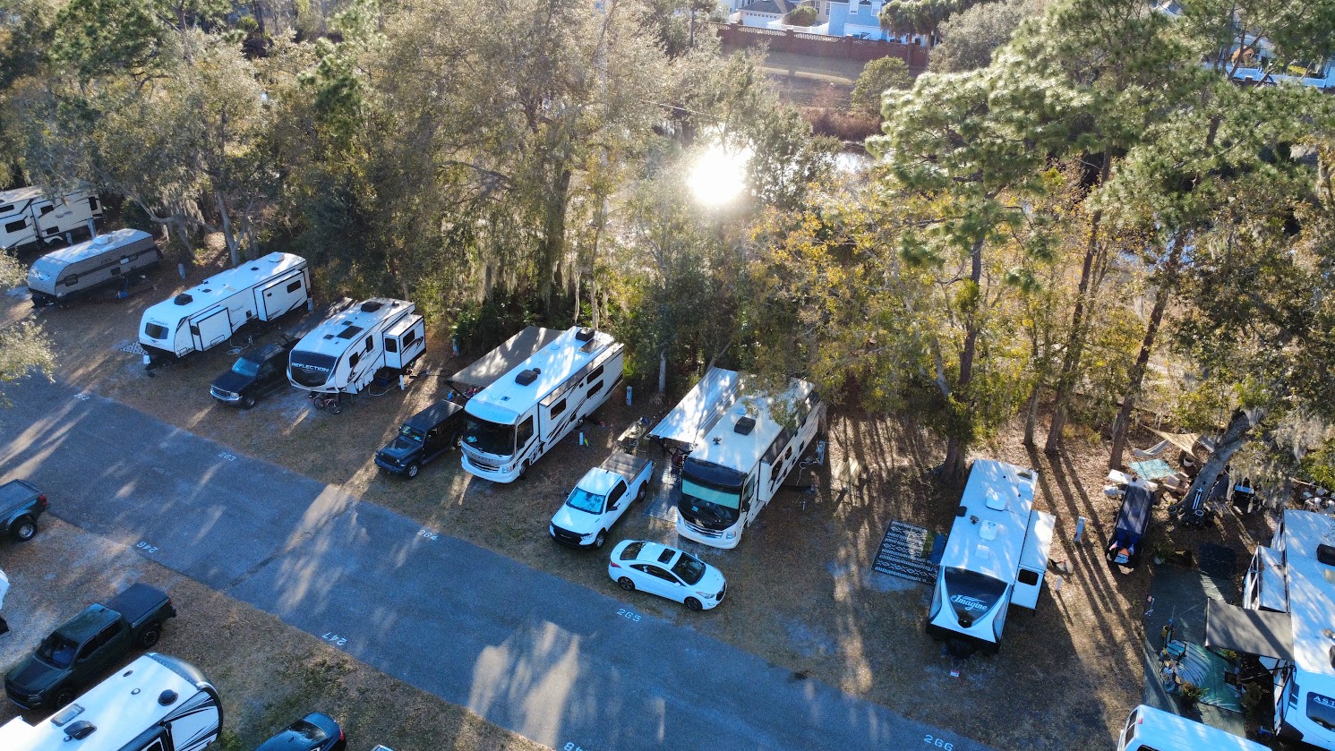Aerial view of RVs parked along a road, surrounded by trees.