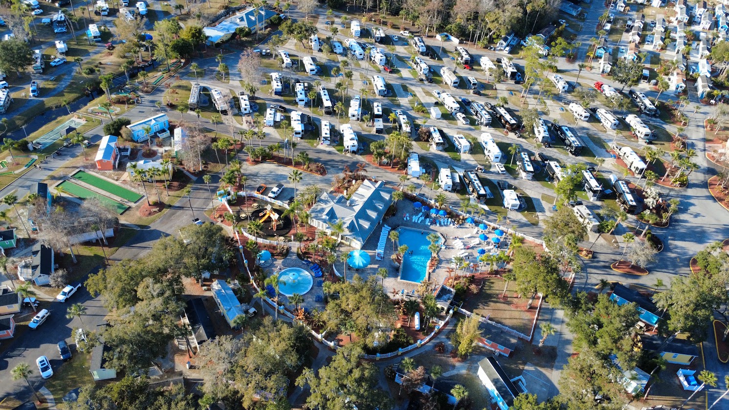 Aerial view of a busy RV resort featuring a pool and recreational areas.