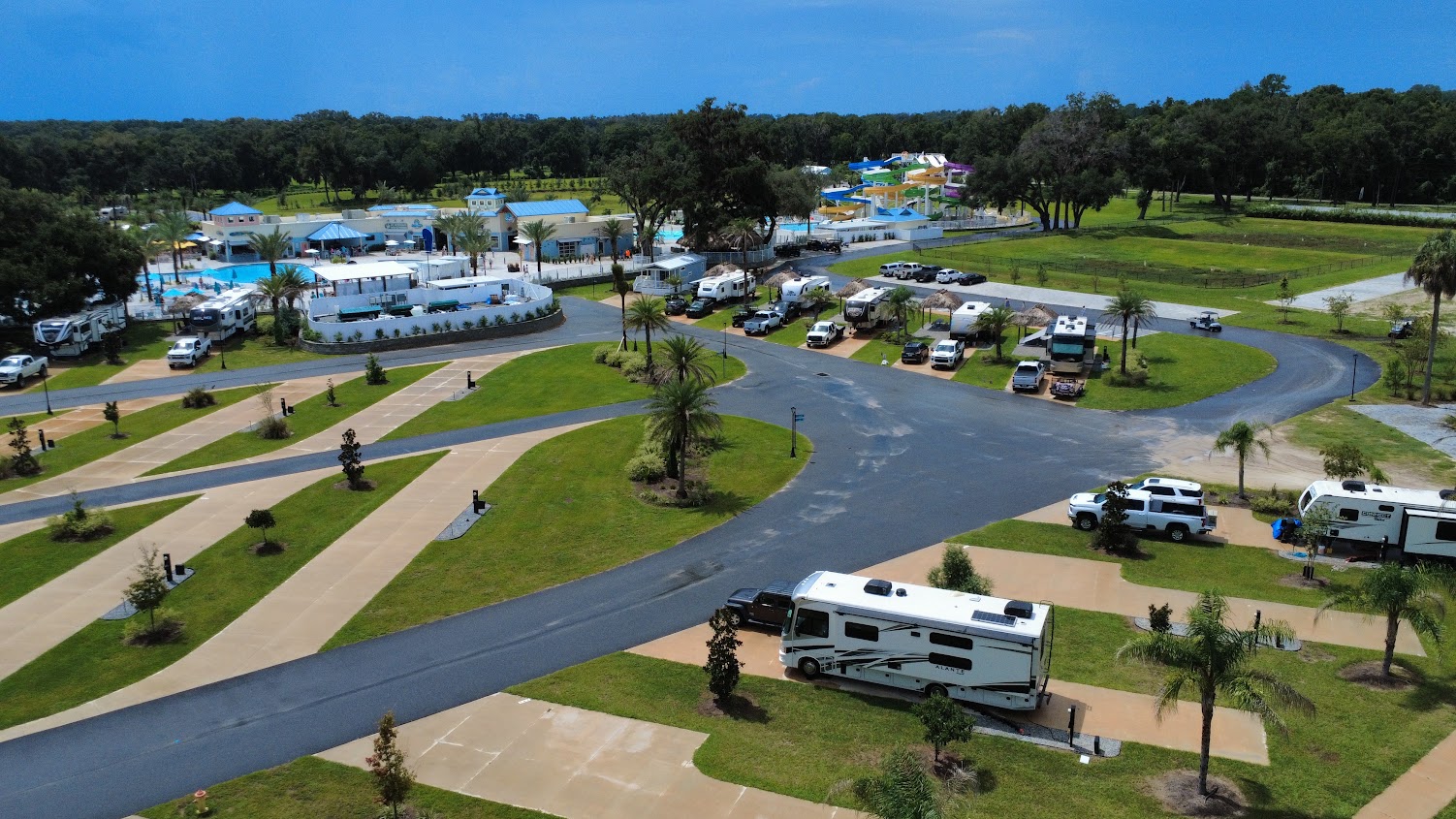Overview of the RV park with multiple RVs and a pool area.