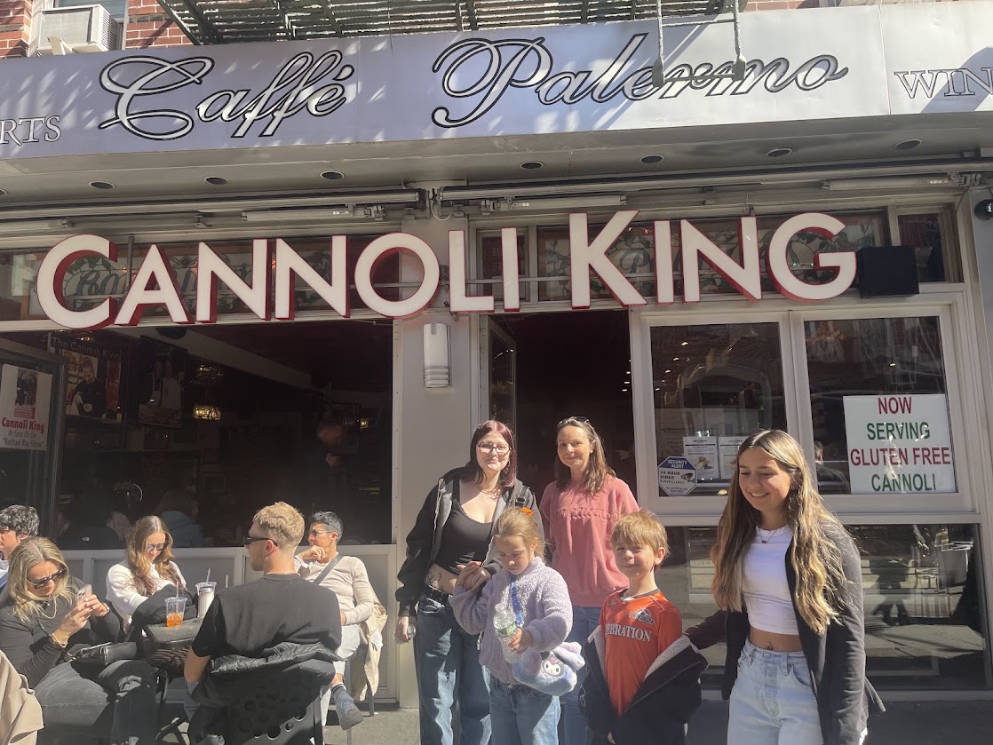 A group of five people standing outside Caffe Palermo beneath a Cannoli King sign.