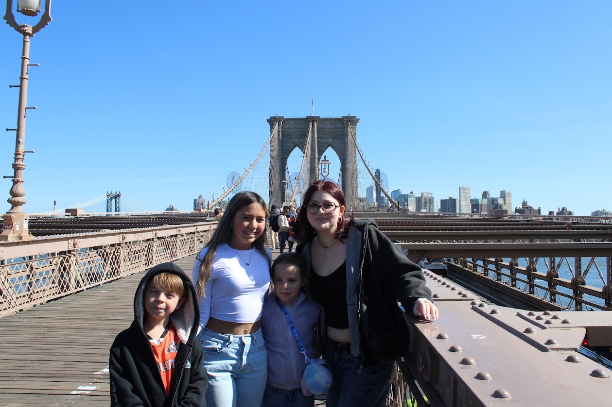 Four children posing on the Brooklyn Bridge with the structure in the background.