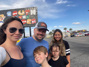 Family poses in front of the South of the Border sign under a blue sky.