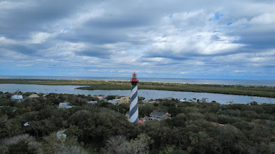 Aerial view of St. Augustine Lighthouse surrounded by greenery and a body of water.