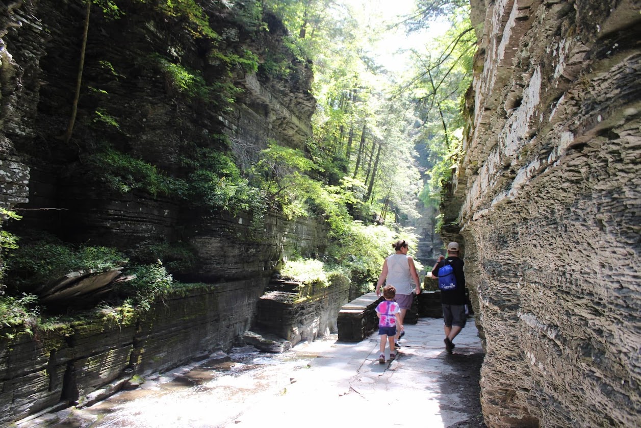 A family walking along a rocky path between tall stone walls.