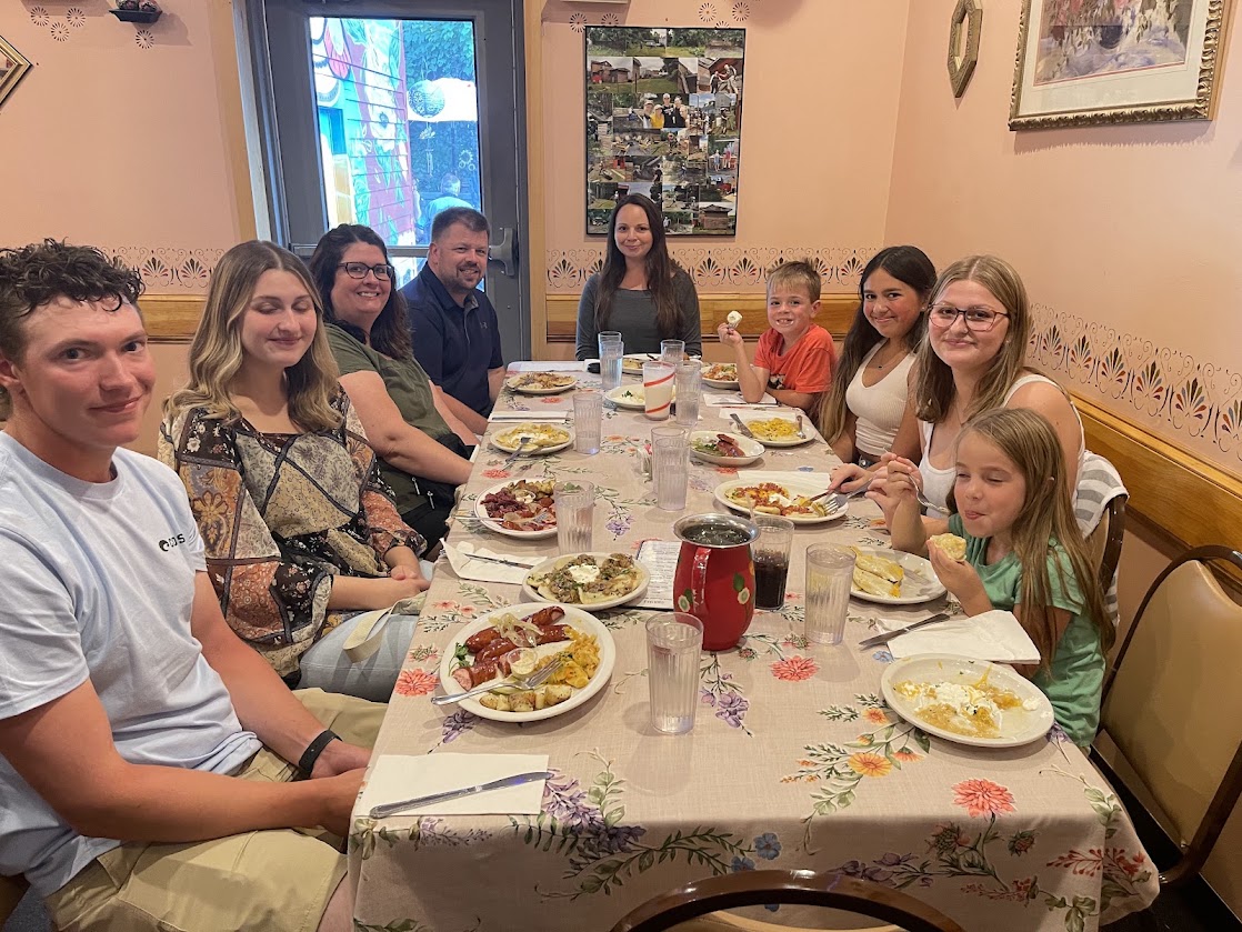 Group of people seated at a dining table with various plates of food.