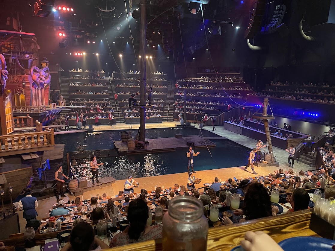 Performance scene at Pirate's Dinner Adventure, with actors on stage and audience in the background.