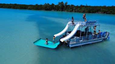 A pontoon boat with water slides in clear water, surrounded by greenery in Sugarloaf Key.