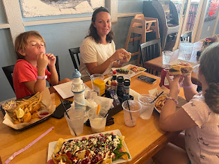 A family dining at Kikis Sandbar, enjoying plates of food including fries and nachos.