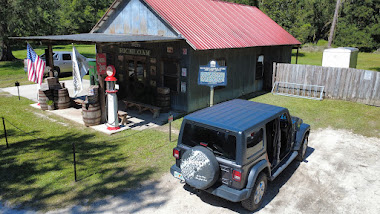 A black Jeep parked near the Richloam General Store with a red roof and surrounding greenery.