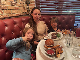 A woman sitting at a booth with two children, enjoying dinner at a restaurant.