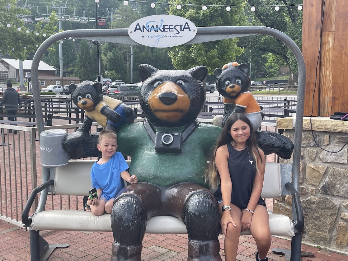 A young boy and girl sit on a bear statue at Anakeesta, Gatlinburg.