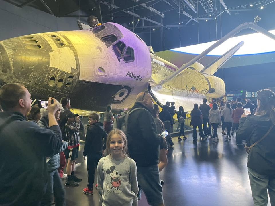 Visitors admire Space Shuttle Atlantis in a crowded exhibit hall.