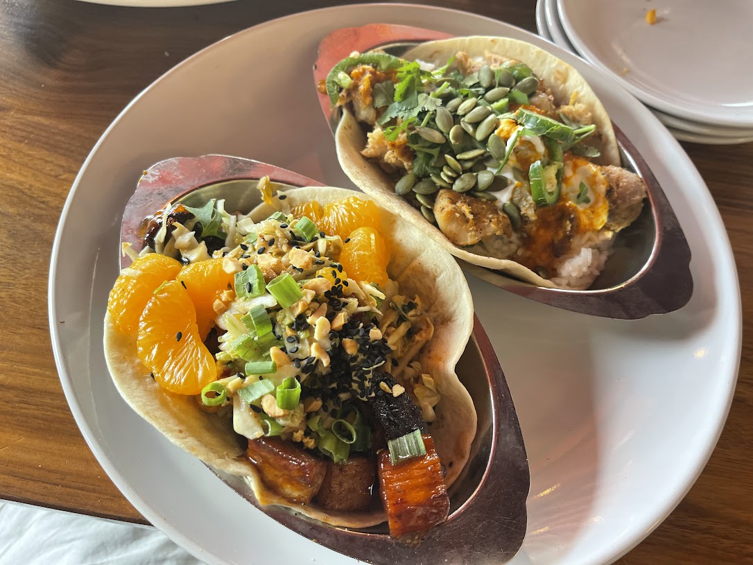Butter Chicken Taco next to a Pork Belly Taco with fresh Slaw