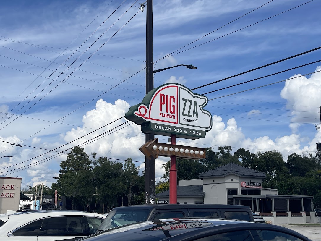 The Pigzza restaurant sign at the entrance, featuring the logo and urban BBQ theme.