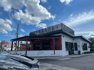 Exterior view of the Pigzza restaurant with a red facade and a rooftop seating area.