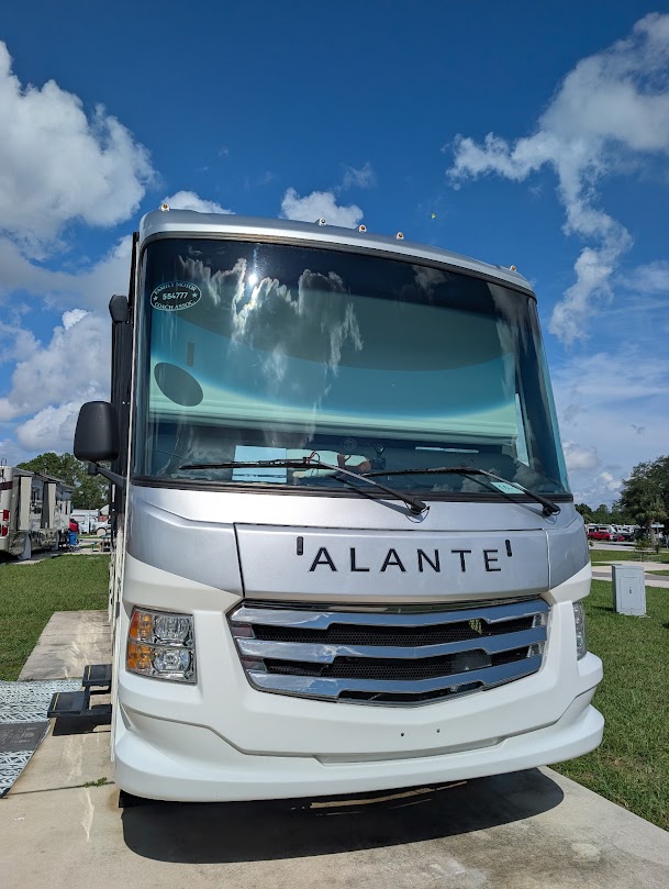 Front view of a 'ALANTE' RV under a blue sky with clouds.
